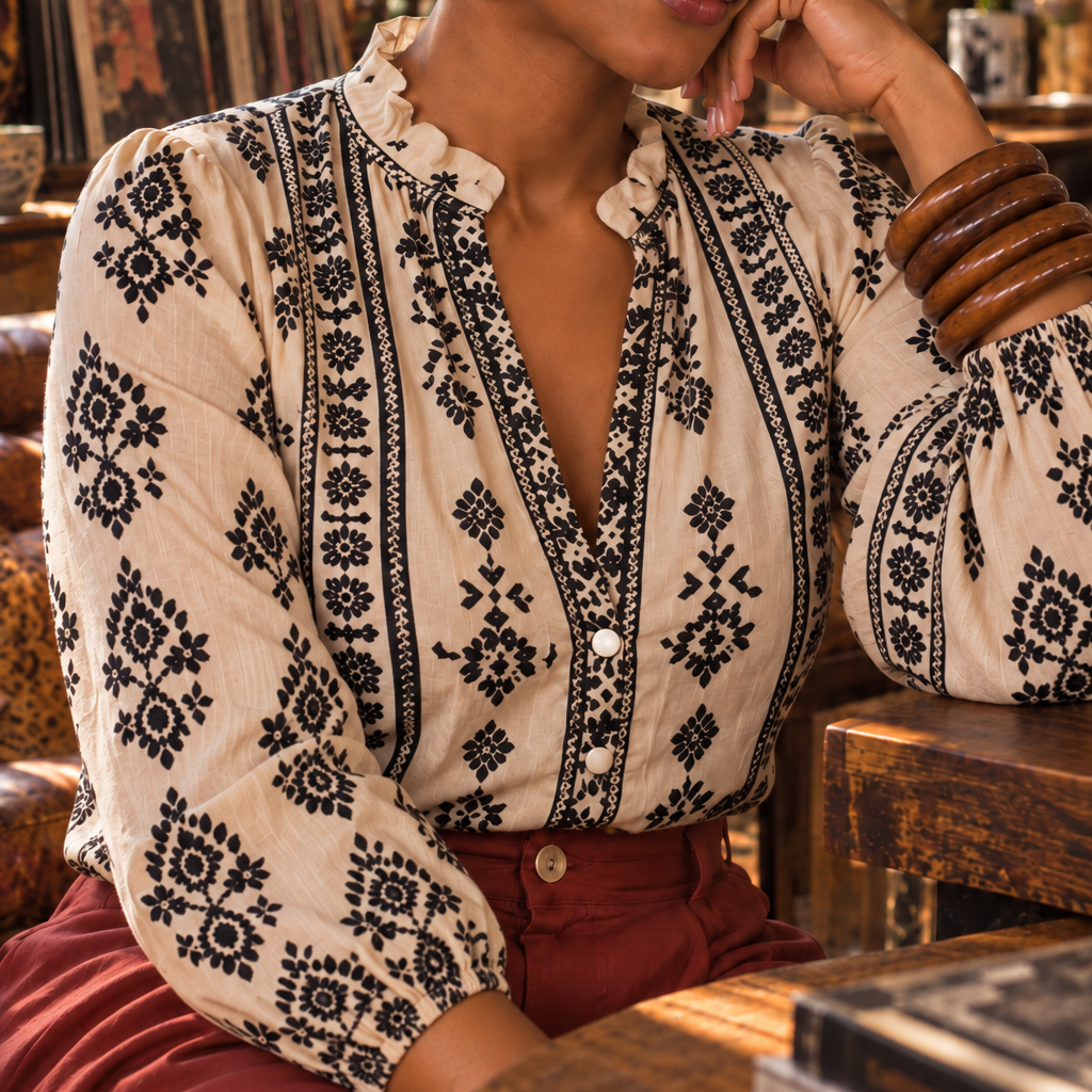 Woman wearing Maria Pattern Blouse with top buttons loose and red pants.